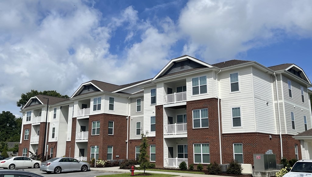 a brick and white apartment building with cars parked in front