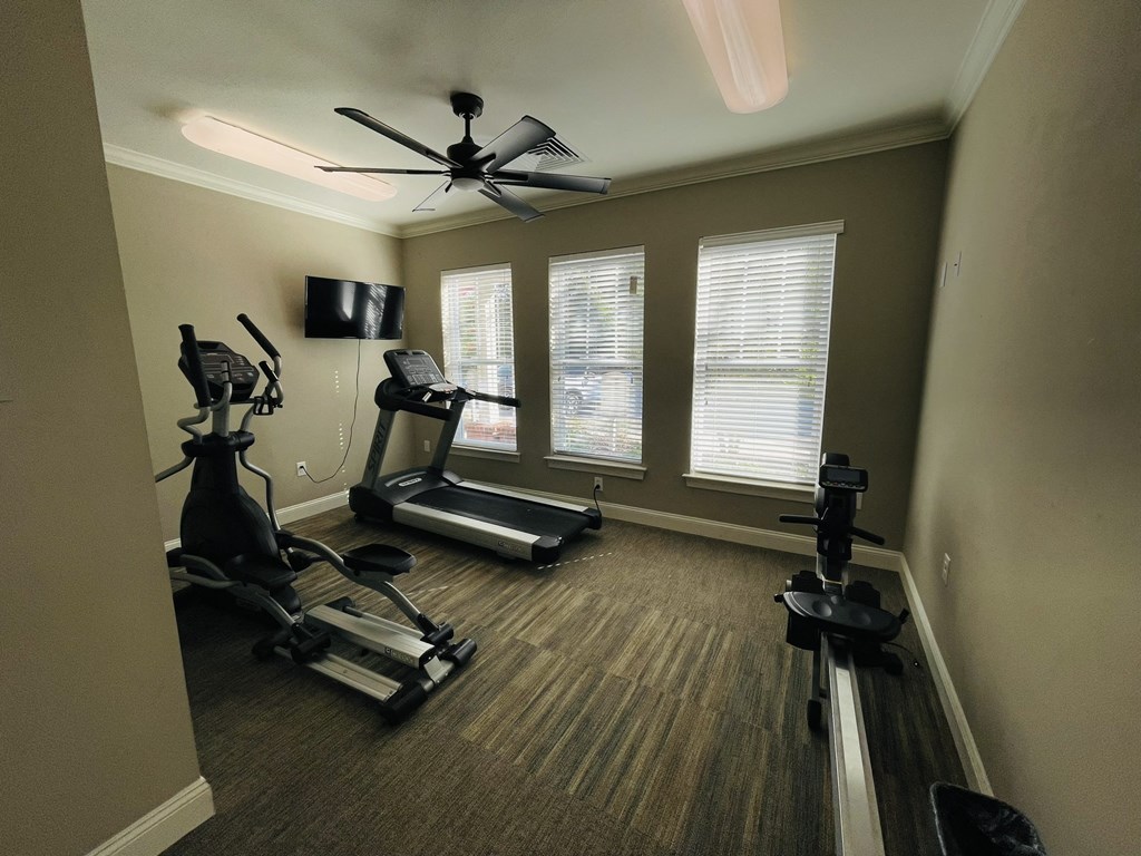 a home gym with exercise machines and a ceiling fan
