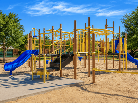 A playground with a yellow structure and a blue slide.