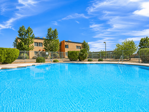 A swimming pool in front of a building with a fence around it.