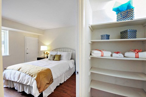 A bedroom with a bed and a closet with shelves.