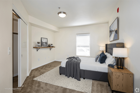 A bedroom with a bed, nightstand, and a window.