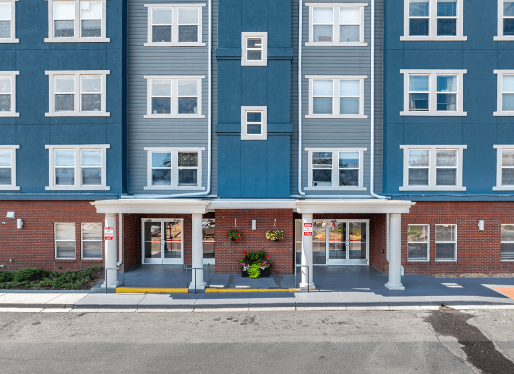 A large building with a red brick base and grey upper floors.