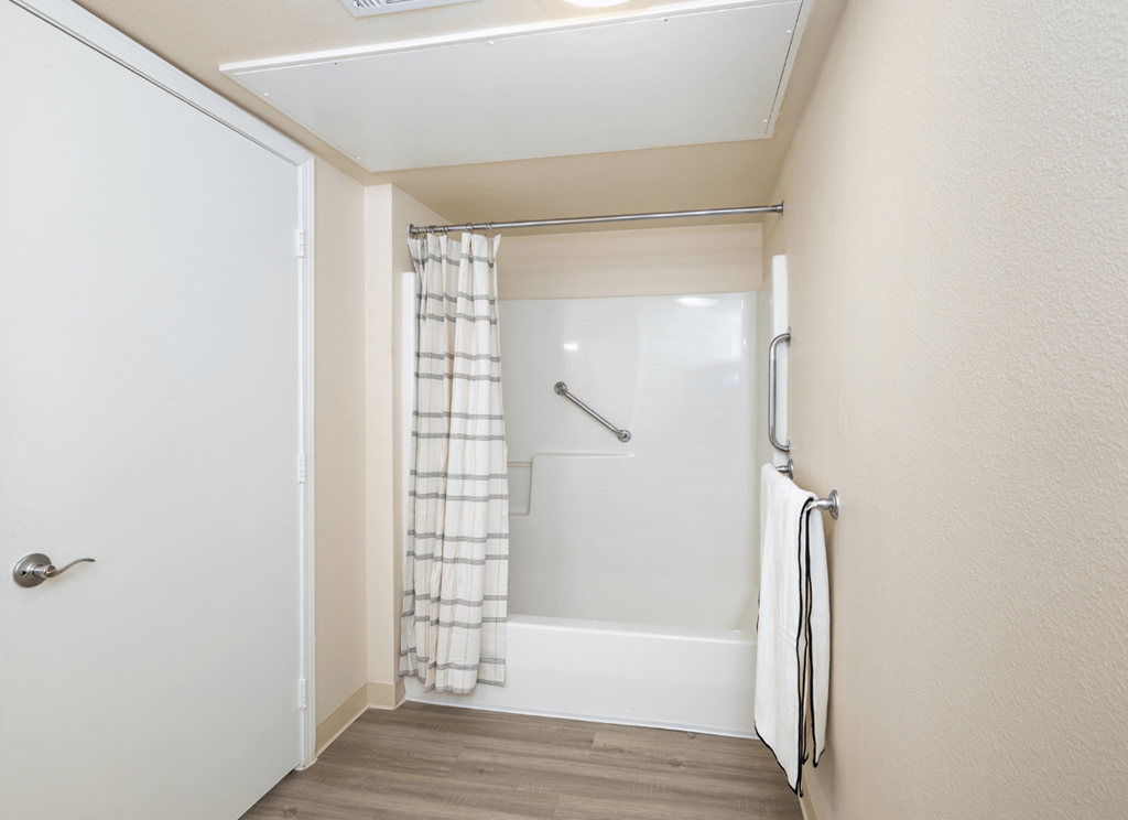 A white door is open to a bathroom with a shower curtain.