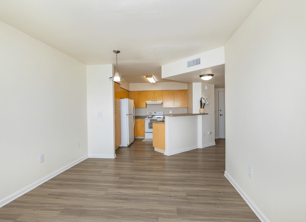A kitchen with white walls and wooden floors.