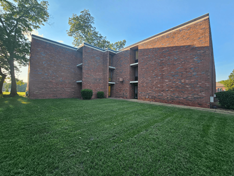 A red brick building with a green lawn in front.