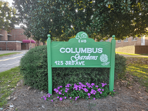 a sign gardens in front of a tree