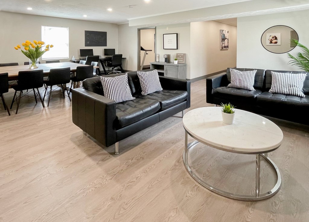 A living room with a black couch and a white coffee table.