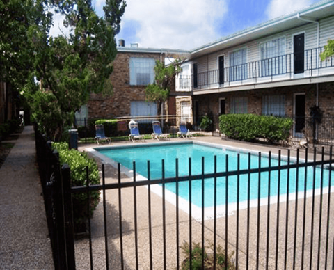 A black fence surrounds a small pool in a residential area.