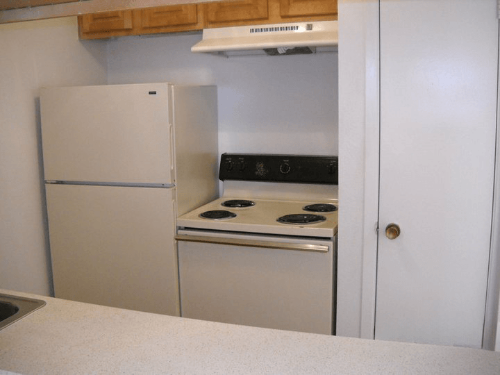 a white kitchen with a stove and a refrigerator