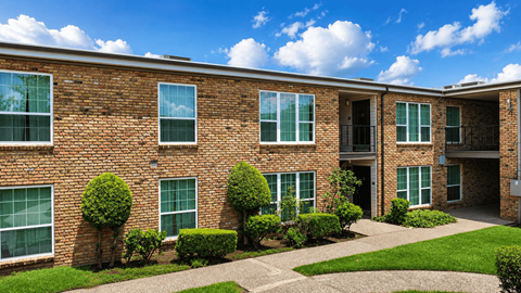 A brick building with green bushes in front.
