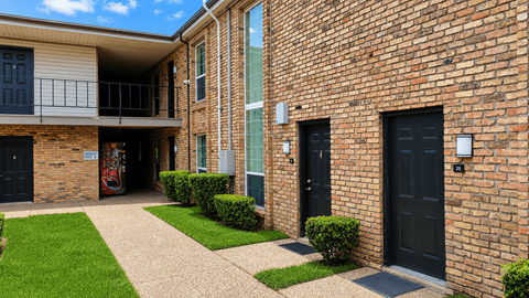 A brick building with a balcony and black doors.