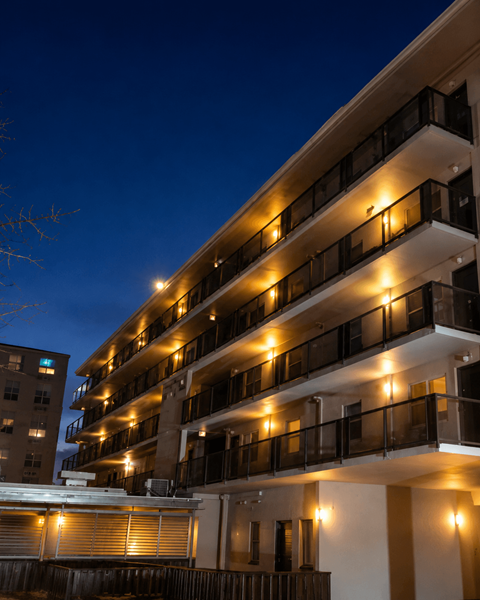 A building with balconies lit up at night.