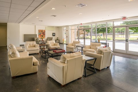 A spacious waiting room with white furniture and a view of the outside.