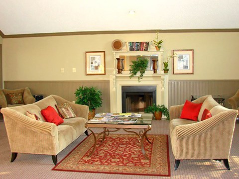 A living room with two chairs, a coffee table, and a fireplace.