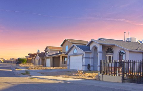 a row of houses on a street at sunset