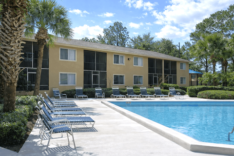 A pool area with chairs and a building in the background.