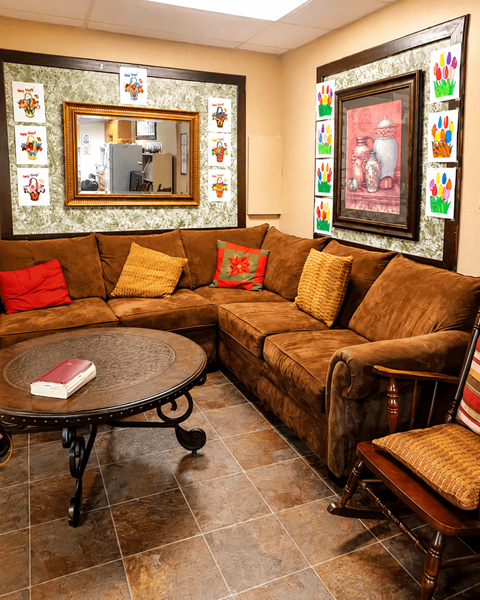 A living room with a brown couch, a round table, and a mirror on the wall.