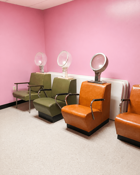 Three chairs and two mirrors in a room.