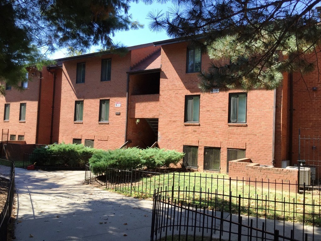 A red brick building with a black fence in front.
