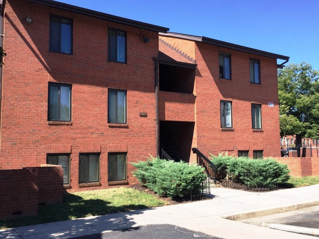 A red brick building with a black railing on the balcony.