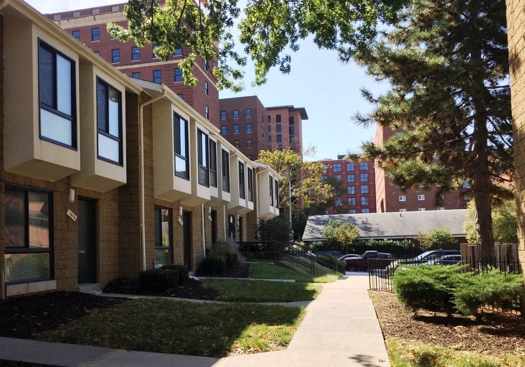 A long row of identical buildings with a sidewalk in front of them.