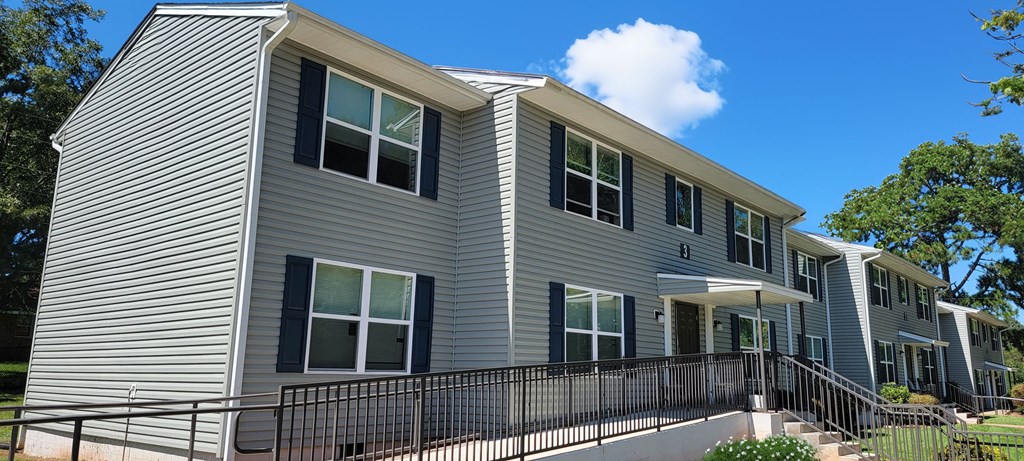 a gray apartment building with a balcony and a blue sky