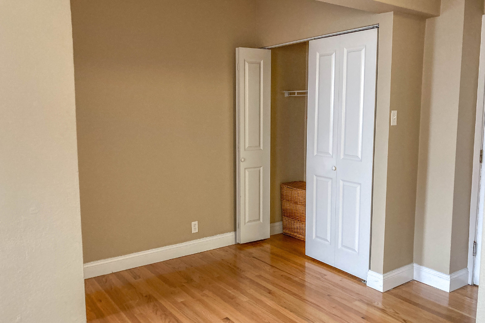a bedroom with a door open to a closet and a wooden floor