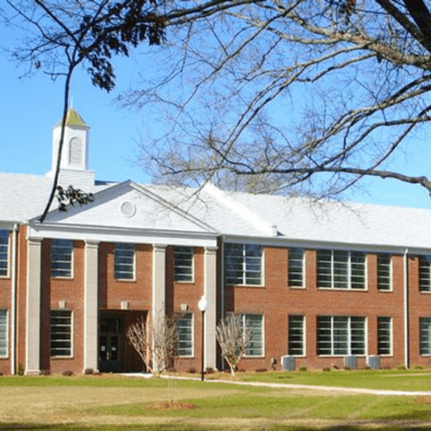 A large red brick building with a white tower and a clock on the front.