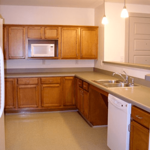 A kitchen with wooden cabinets and a white dishwasher.