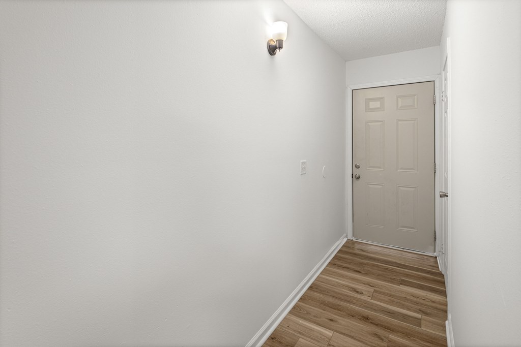A white door is in a room with a light switch on the wall.