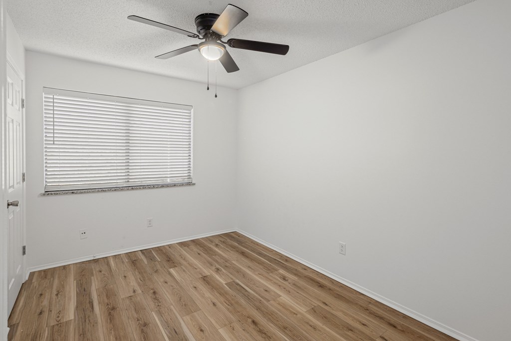 A room with a ceiling fan and wooden flooring.