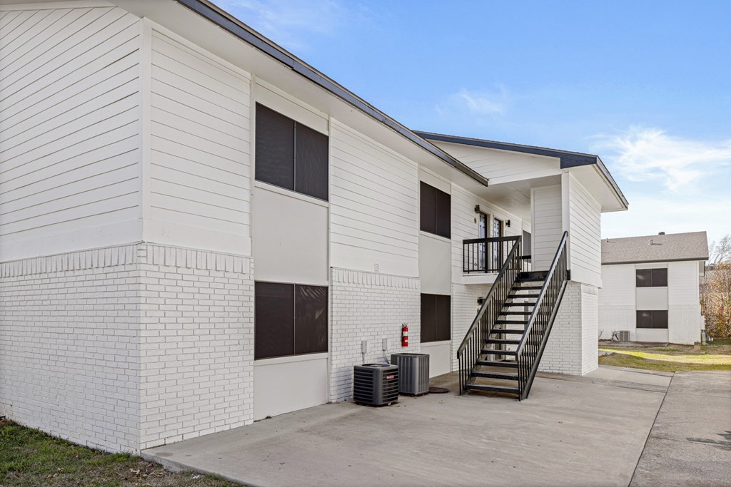 A white building with a black staircase leading to the second floor.