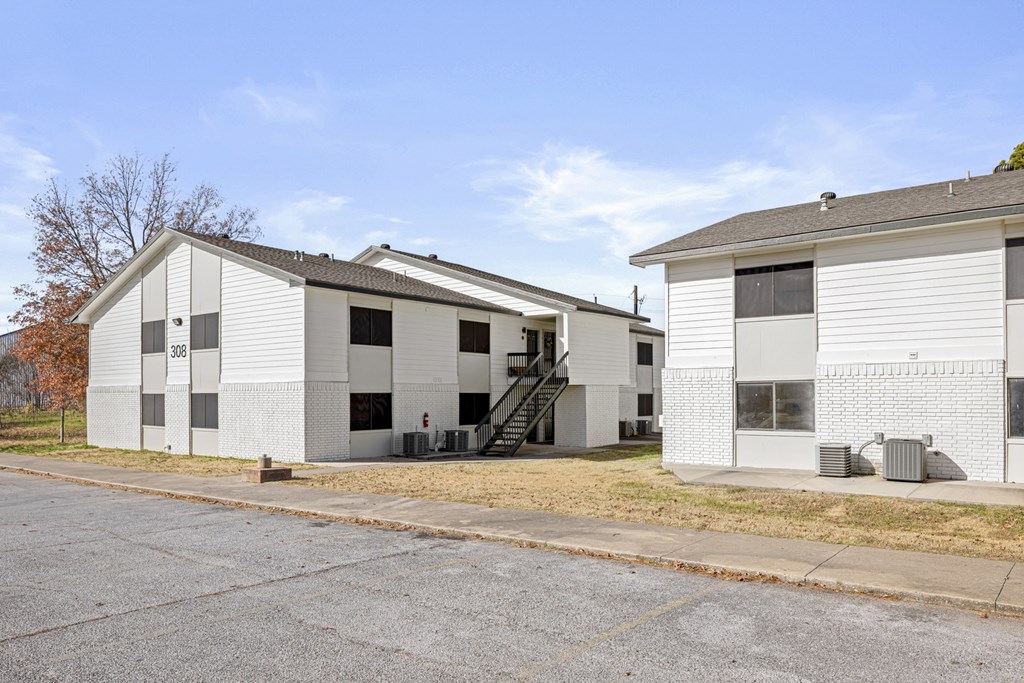 A white building with a grey roof and a sign that reads 338 is situated next to a smaller white building.