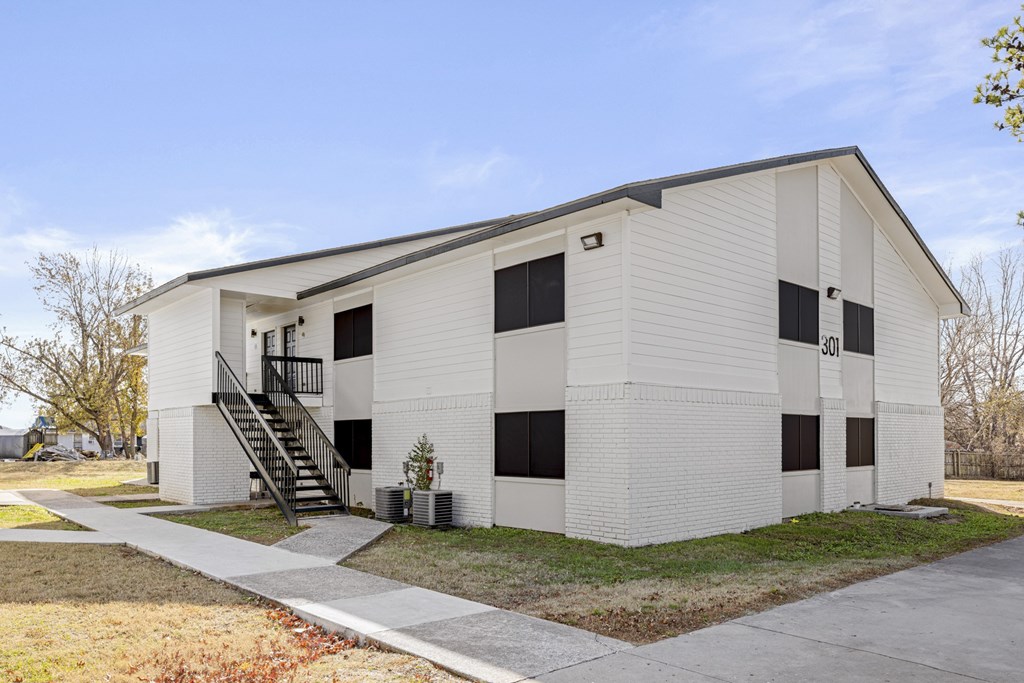 A white building with black windows and a staircase leading to the second floor.