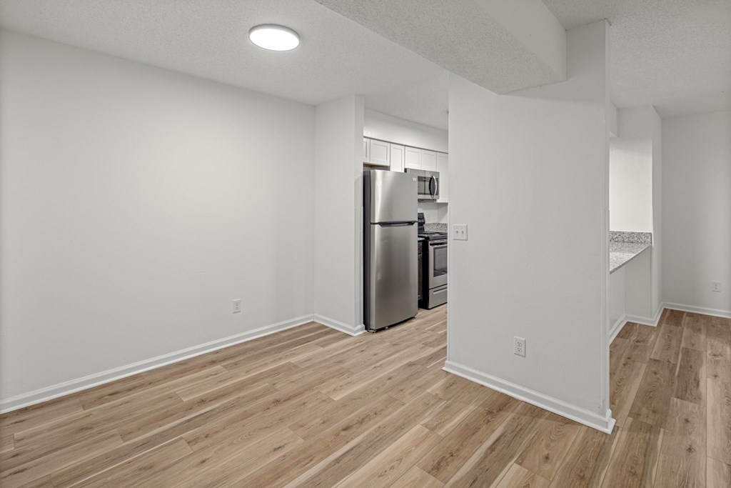 A kitchen with a refrigerator and wooden floors.