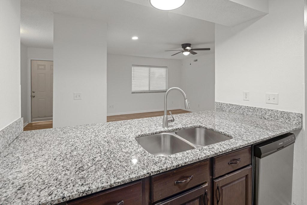 A kitchen with granite countertops and a stainless steel sink.