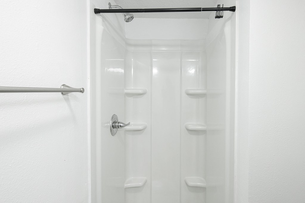 A white bathroom with a shower and a toilet.