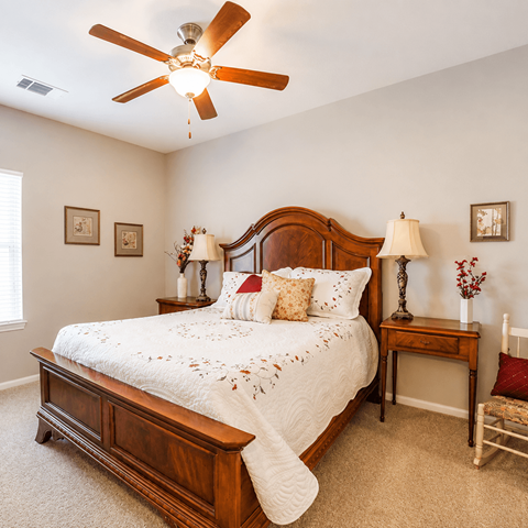 A bedroom with a large bed and a ceiling fan.
