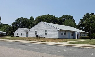 A white building with a grey roof is surrounded by a parking lot.
