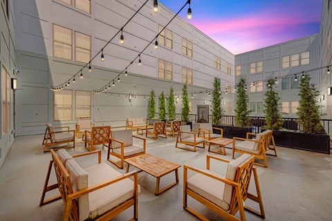 A patio with wooden furniture and string lights.