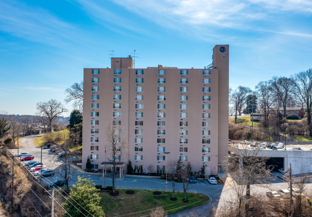 a tall building with many windows and a parking lot in front of it