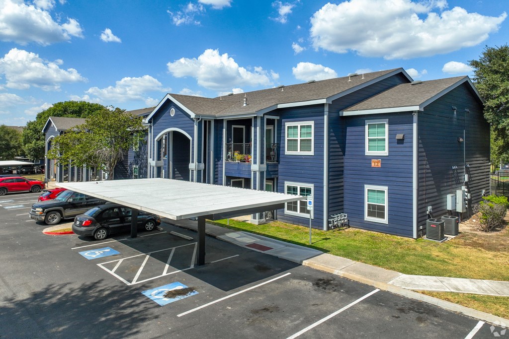 A blue building with a covered parking area in front.