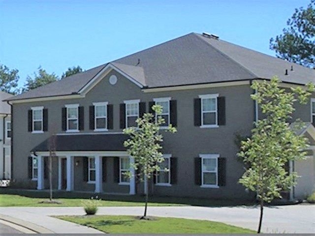 a large gray house with trees in front of it