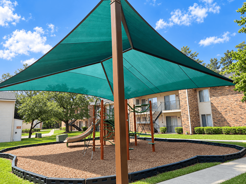 A playground with a green canopy and a slide.