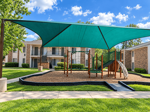 A playground with a green canopy and a slide.