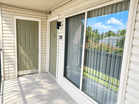 A white house with a green door and a sliding glass door.