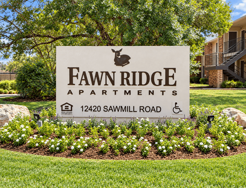 A sign for Fawn Ridge Apartments is surrounded by flowers.