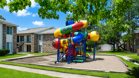 A colorful playground structure with a slide in the middle of a grassy area.