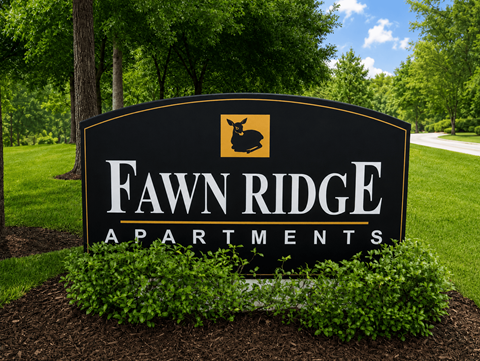A sign for Fawn Ridge Apartments is shown in front of a green lawn.